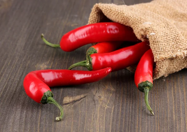 Red hot chili peppers in bag on wooden background — Stock Photo, Image