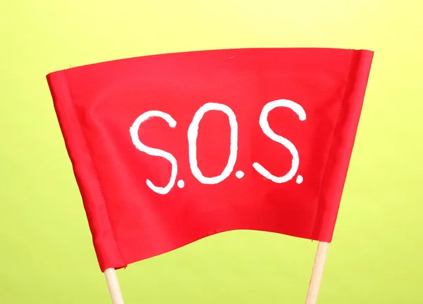SOS сигнал написан на красной ткани на зеленом фоне — стоковое фото