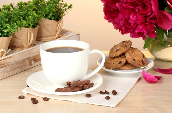 Cup of coffee, cookies, chocolate and flowers on table in cafe — Stock Photo, Image