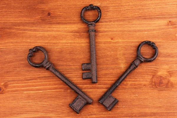 Three antique keys on wooden background — Stock Photo, Image