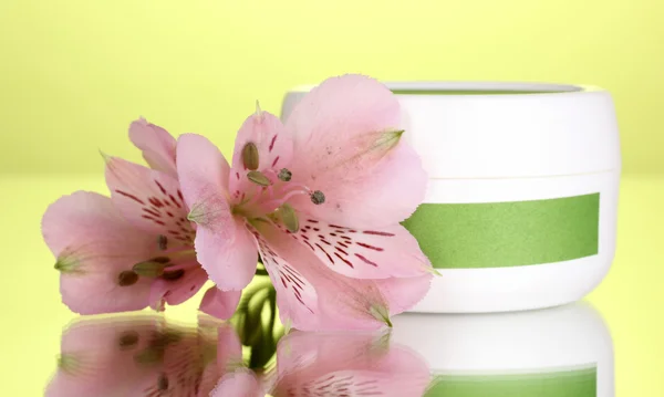 Tarro de crema con flor sobre fondo verde — Foto de Stock