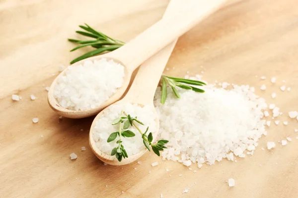 Salt in spoons with fresh rosemary and thyme on wooden background — Stock Photo, Image