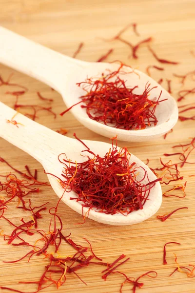 Stigmas of saffron in wooden spoons on wooden background close-up — Stock Photo, Image