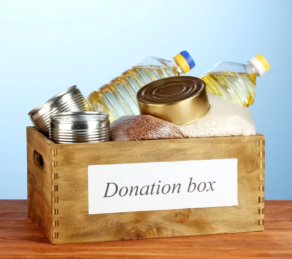 Donatie box met voedsel op blauwe achtergrond close-up — Stockfoto