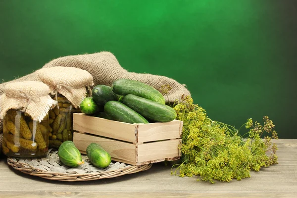 Färska gurkor i trälåda, pickles och dill, på grön bakgrund — Stockfoto