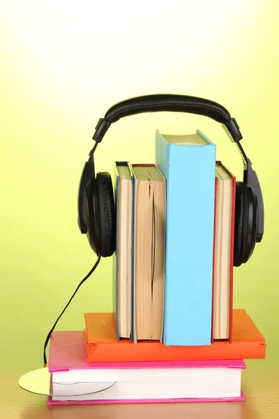 Kopfhörer auf Bücher auf Holztisch auf grünem Hintergrund — Stockfoto