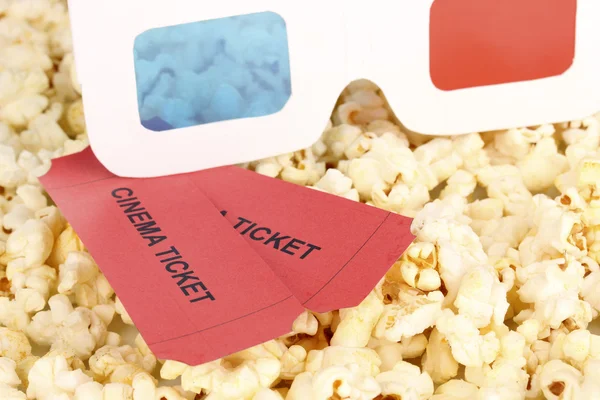 Cinema tickets and glasses on popcorn background