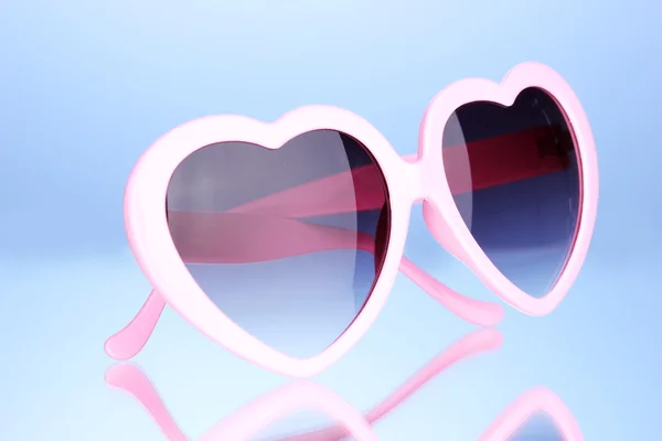 Pink heart-shaped sunglasses on blue background — Stock Photo, Image
