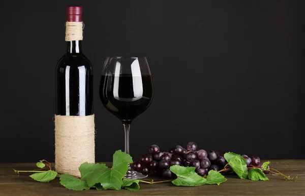 포도와 와인의 병 잎에 검은 배경에 나무 테이블 — 스톡 사진
