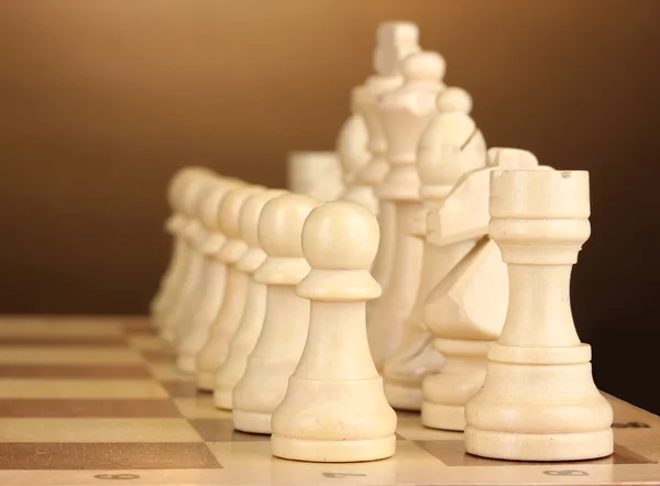 Tablero de ajedrez con piezas de ajedrez sobre fondo marrón — Foto de Stock