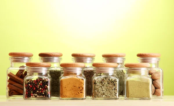 Pulver kryddor i glasburkar på grön bakgrund — Stockfoto