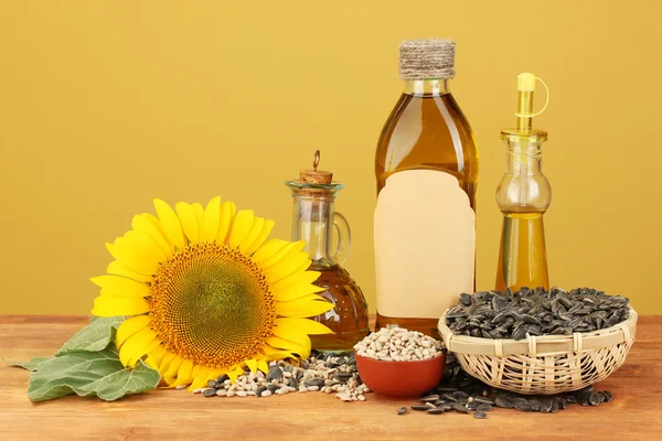 Olej slunečnicový a sunflower na žlutém podkladu — Stock fotografie