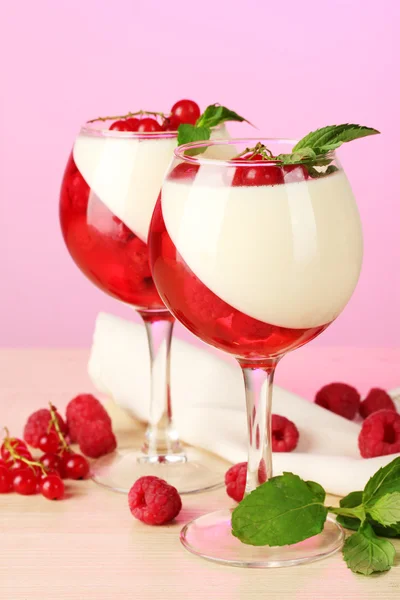 Jelly buah dengan buah dalam gelas di atas meja kayu di latar belakang merah muda — Stok Foto