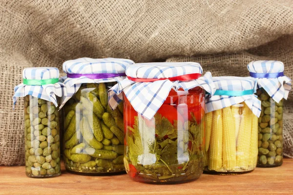 Banks canned vegetables on sack background — Stock Photo, Image