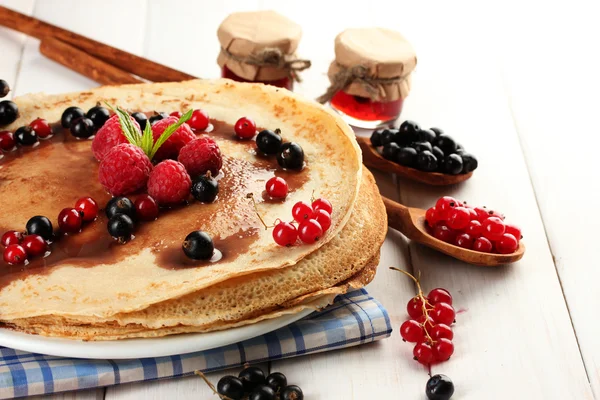 Pancake lezat dengan buah beri dan selai di piring di atas meja kayu — Stok Foto