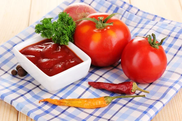 Keczup i dojrzałe pomidory na drewnianym stole — Zdjęcie stockowe