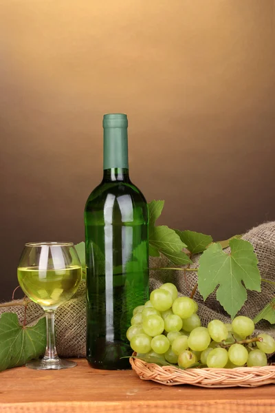 Botella de gran vino con copa sobre mesa de madera sobre fondo marrón — Foto de Stock