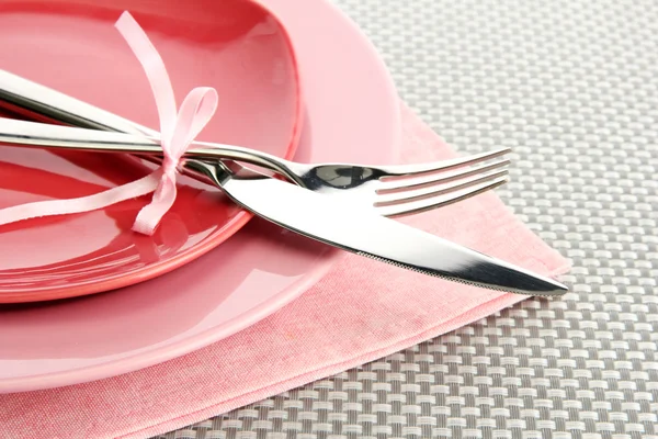 Platos vacíos rosados con tenedor y cuchillo sobre un mantel gris — Foto de Stock