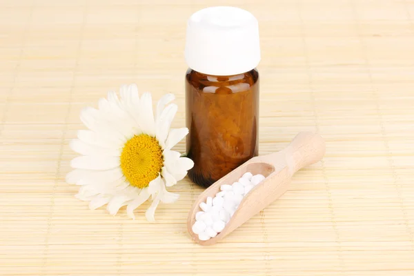 Frasco de medicamento com comprimidos e flor na esteira de bambu — Fotografia de Stock