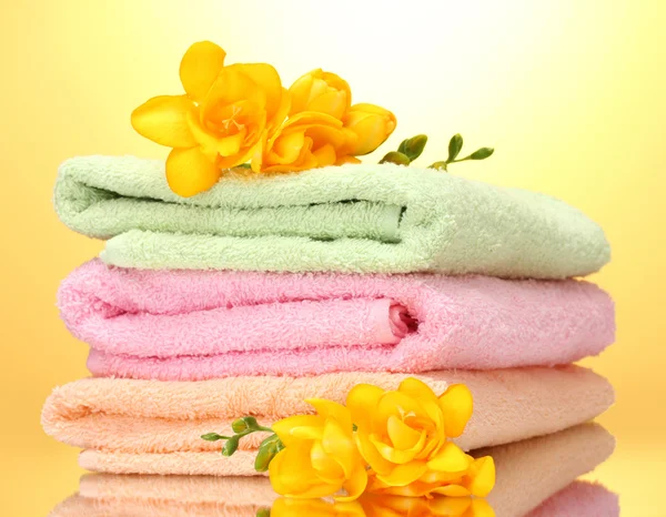 Bunte Handtücher und Blumen auf gelbem Hintergrund — Stockfoto