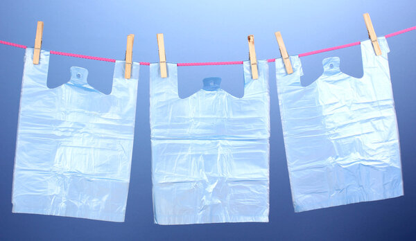 Целофановые мешки висят на веревке на синем фоне
