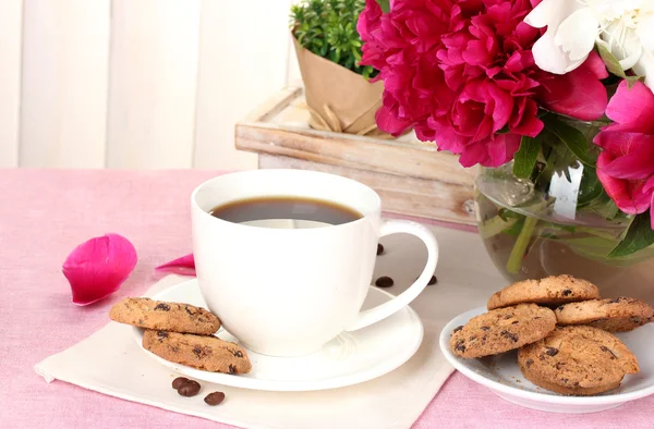 Cup of coffee, cookies and flowers on table in cafe — Stock Photo, Image