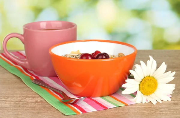 Yeşil zemin üzerine tahta masada kahvaltı kiraz ile lezzetli mısır gevreği — Stok fotoğraf