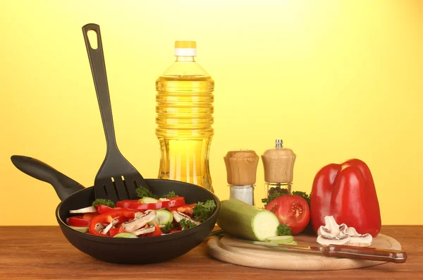 Frying pan with vegetables on yellow background — Stock Photo, Image