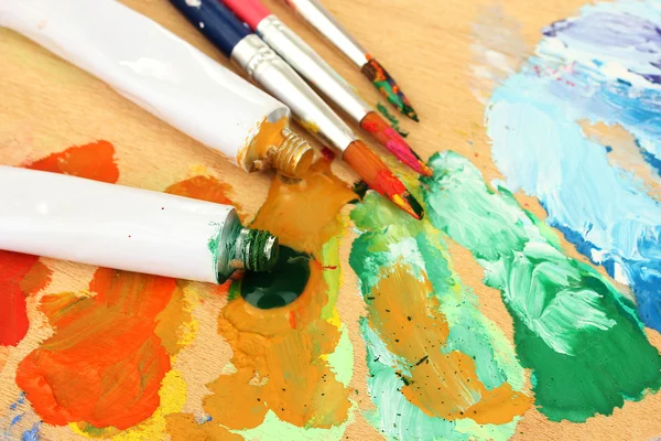 抽象丙烯酸涂料、 油漆管和木制调色板上的画笔 — 图库照片
