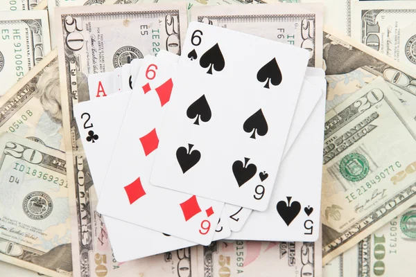 Dólares e um baralho de cartas de baralho em fundo preto close-up — Fotografia de Stock