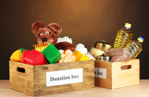 Коробка для пожертвований с едой и детскими игрушками на коричневом фоне крупным планом — стоковое фото
