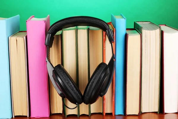 Kopfhörer auf Bücher auf Holztisch auf türkisfarbenem Hintergrund — Stockfoto