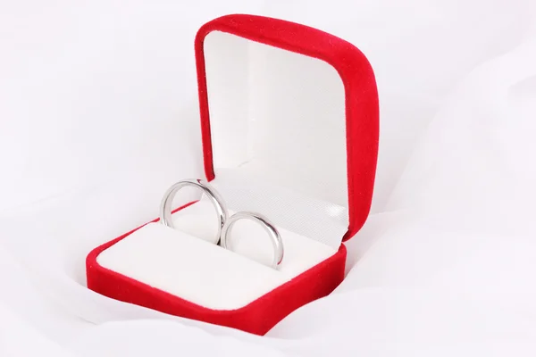 Anéis de casamento em caixa vermelha no fundo pano branco — Fotografia de Stock