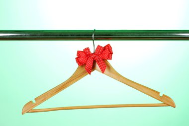 Beautiful red bow hanging on wooden hanger on green background clipart