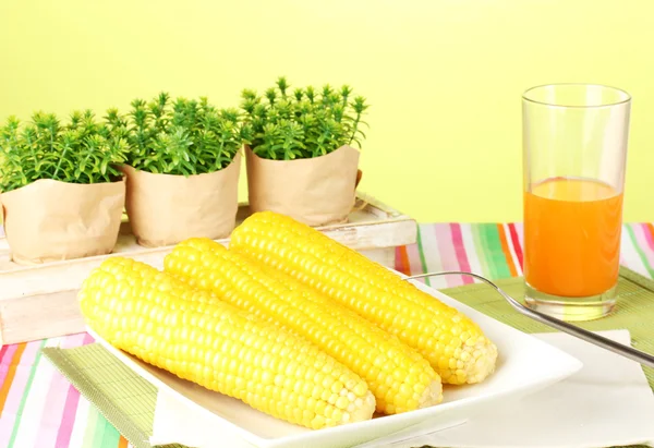 Boiled corn and juice on a green background — Stock Photo, Image
