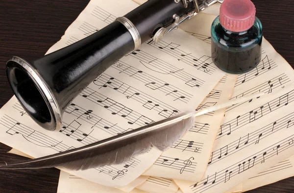 Muzieknoten en klarinet op houten tafel — Stockfoto