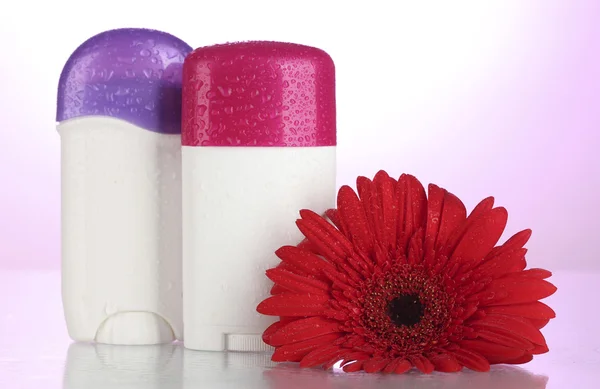 Deodorants with flower on pink background — Stock Photo, Image