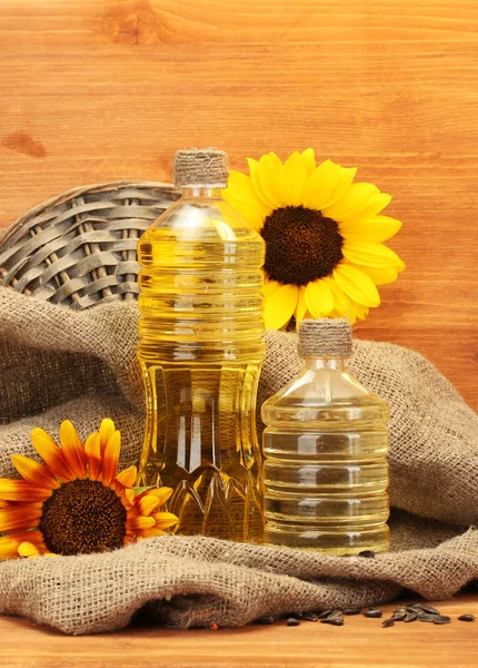 Olja i flaskor, solrosor och frön, på trä bakgrund — Stockfoto