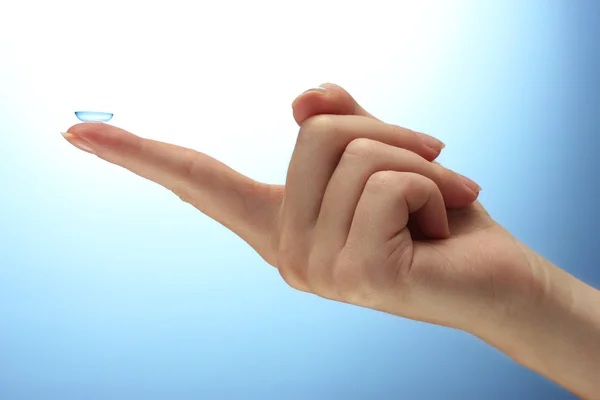 Contact lens on finger on blue background — Stock Photo, Image