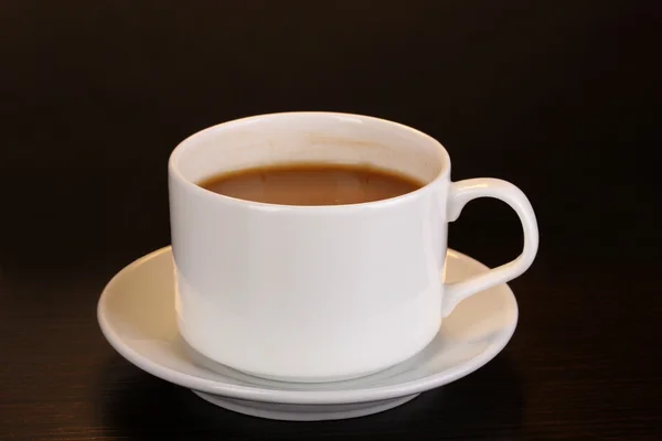 Чашка кави на дерев'яному столі на коричневому фоні — стокове фото