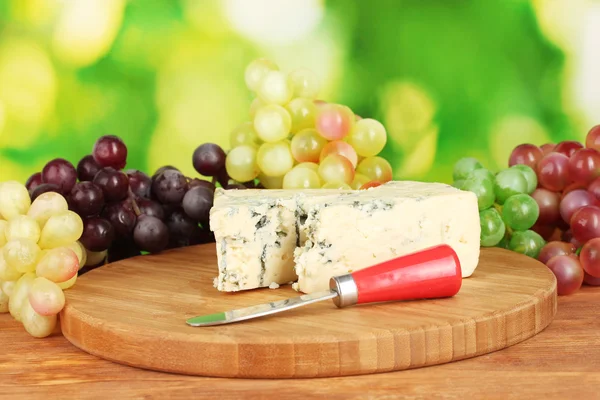 チーズ、まな板の上の明るい緑色の背景でブドウを持つ型 — ストック写真