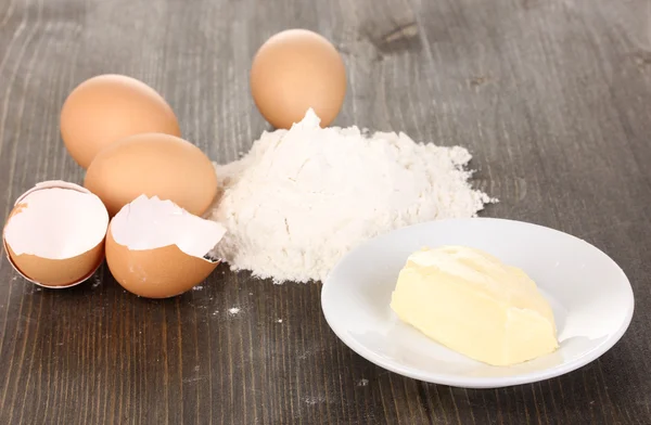 Яйца, мука и масло крупным планом на деревянном столе — стоковое фото
