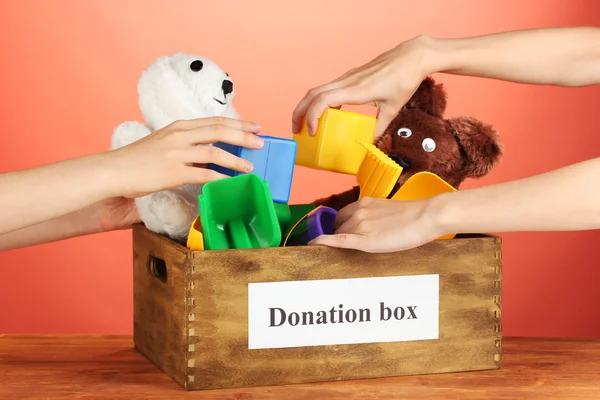 Donation låda med barnleksaker på röd bakgrund närbild — Stockfoto