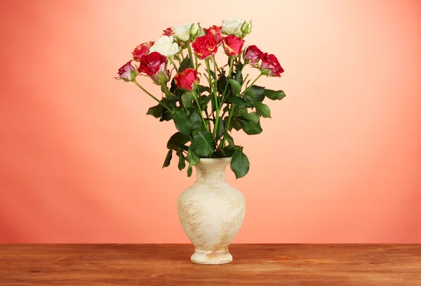 Mooie rozen in vaas op rode achtergrond close-up — Stockfoto