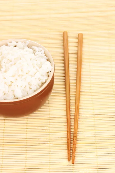 Tigela de arroz e pauzinhos em esteira de bambu — Fotografia de Stock