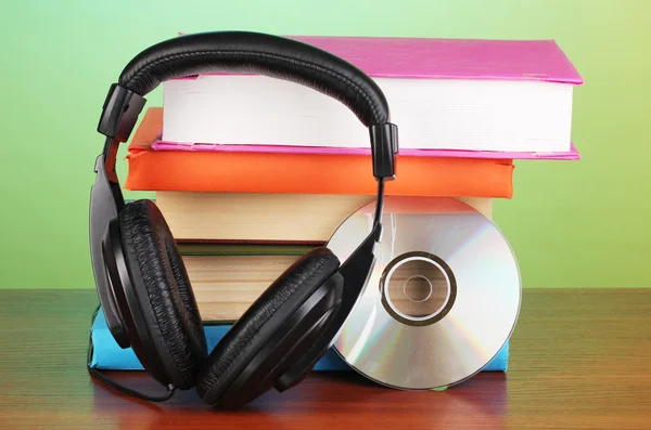 Headphones on books on wooden table on turquoise background — Stock Photo, Image