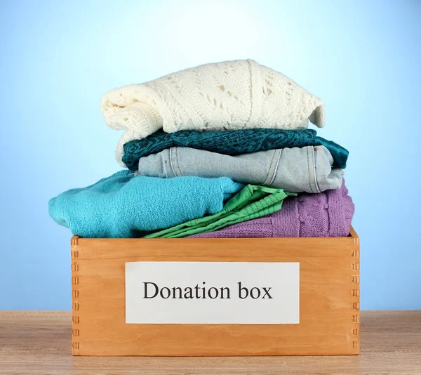 Caixa de doação com roupas em fundo azul close-up — Fotografia de Stock