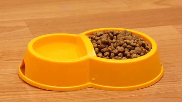 Ξηρά γάτα τροφή και νερό σε κίτρινο μπολ στο πάτωμα — Φωτογραφία Αρχείου