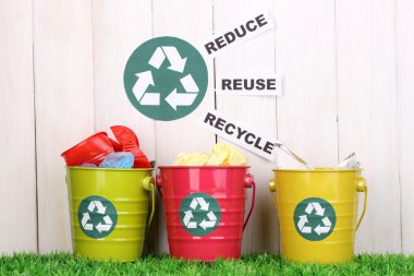 Recycling bins on green grass near wooden fence clipart