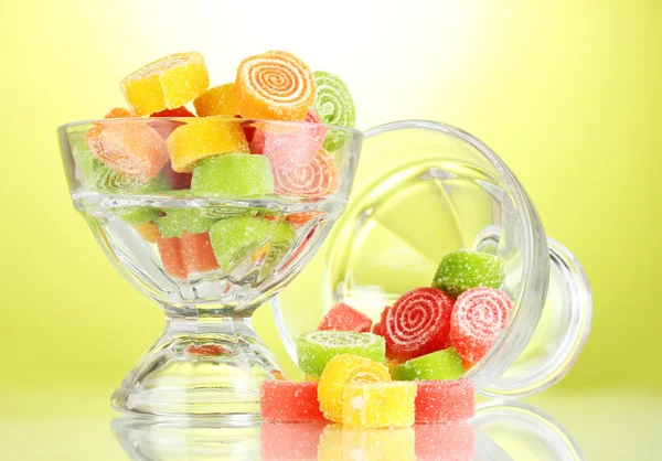 Colorful jelly candies in in glass bowls on green background — Stock Photo, Image